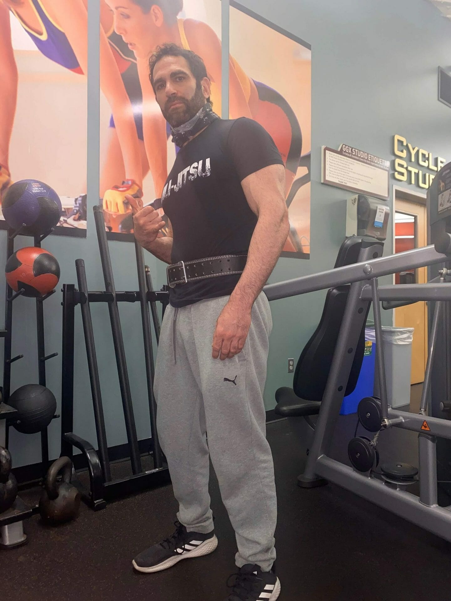 Israel Joffe training in a gym wearing a jiu-jitsu shirt and weightlifting belt
